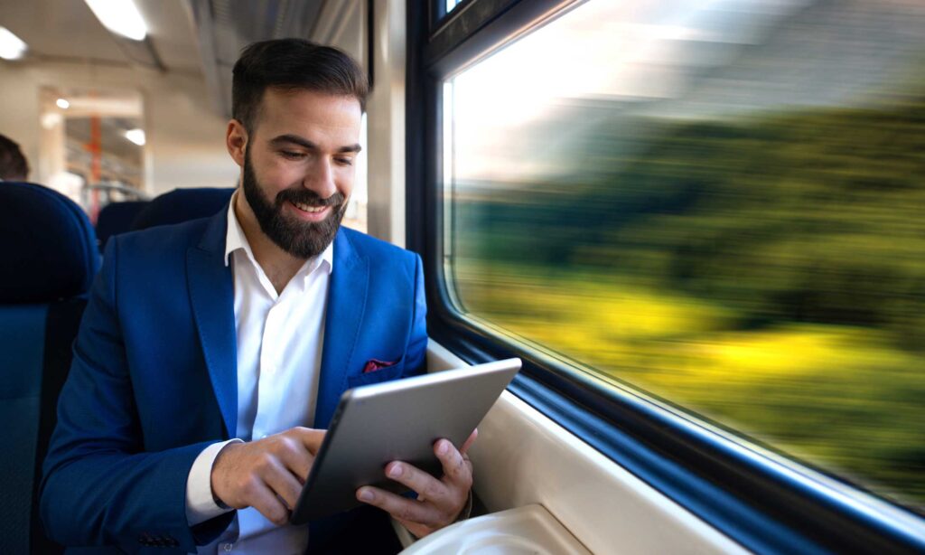 Businessman sitting next to window reading news and surfing internet on his tablet