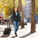 Woman traveler with suitcase along the street