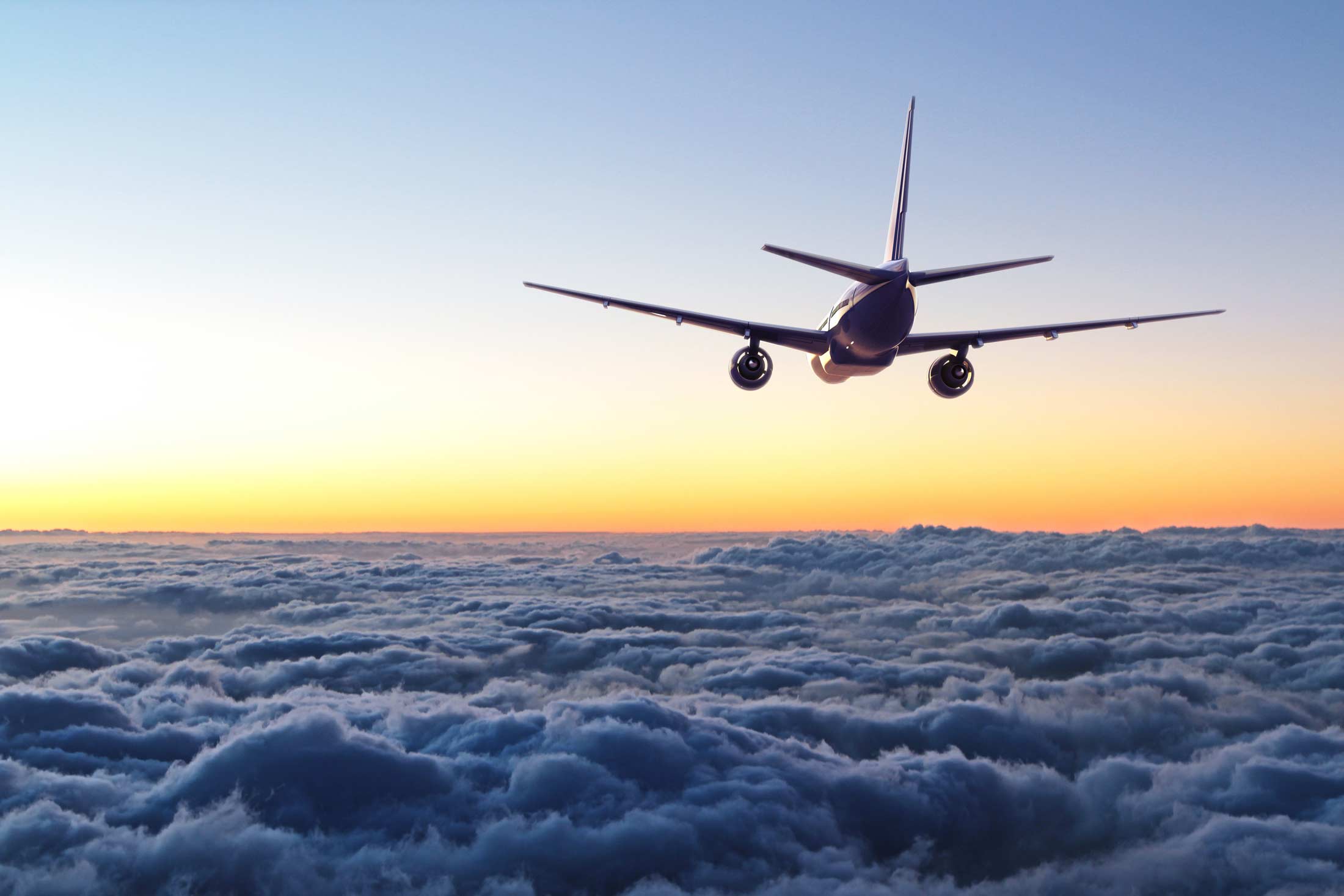 Plane flying toward sunset