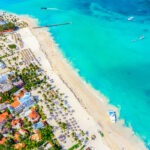 Aerial drone view of beautiful caribbean tropical beach with palms and boats.