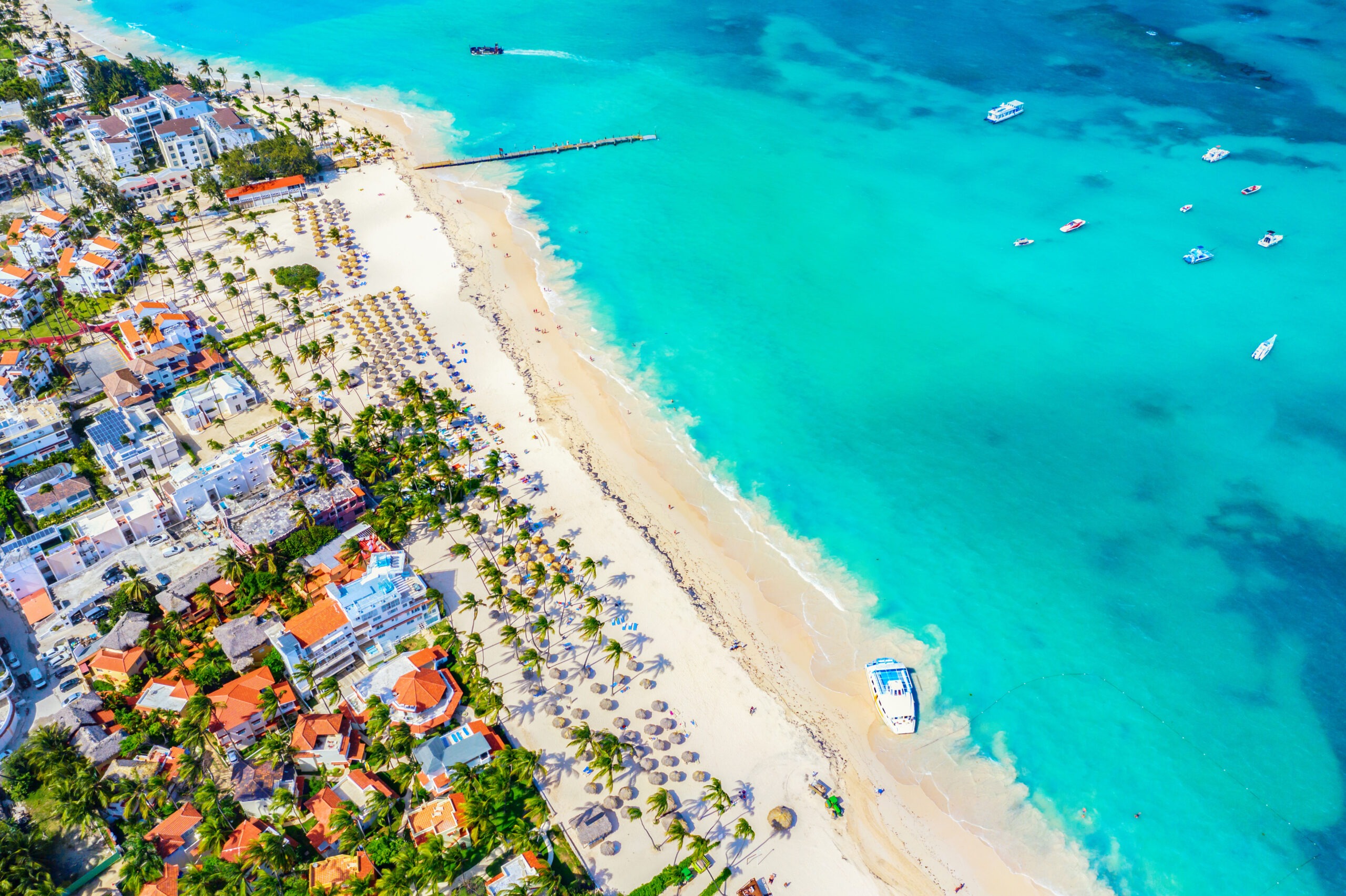 Aerial drone view of beautiful caribbean tropical beach with palms and boats.