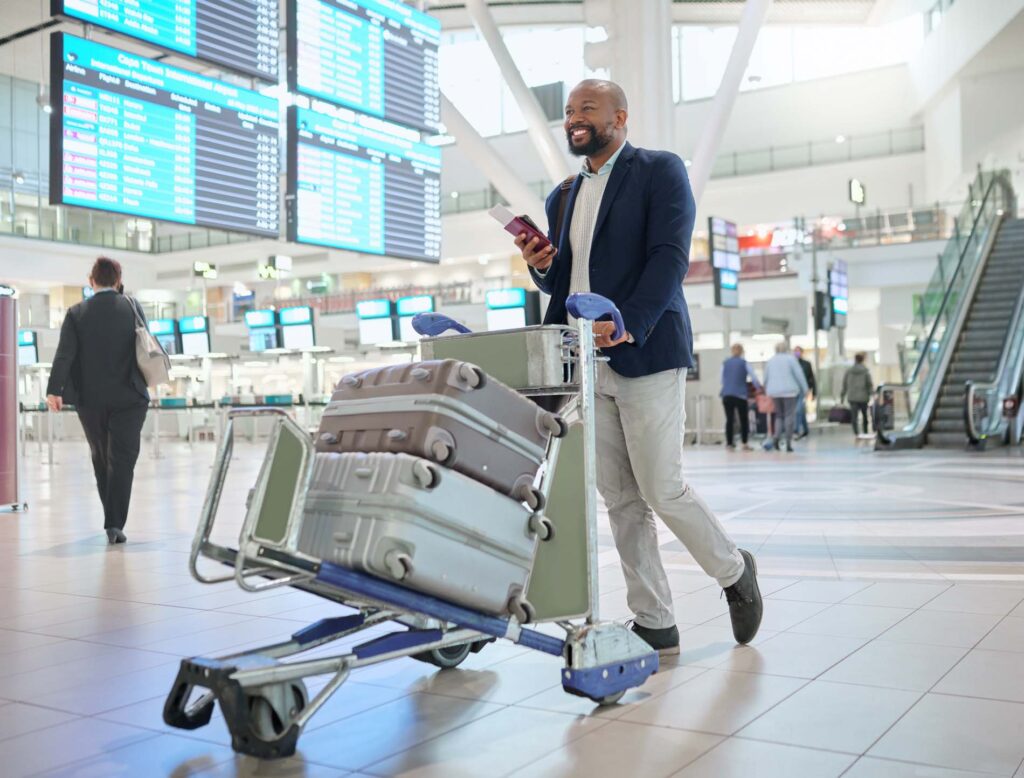 Airport, black man and luggage for travel, smile and business convention with ceo, walking and tourism. African male entrepreneur, corporate leader and employee with suitcases, happiness and commute