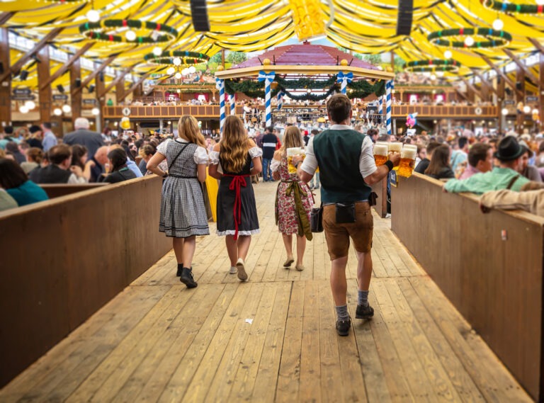 Oktoberfest, Munich, Germany. Waiter with traditional costume holding beers, crowded tent interior background