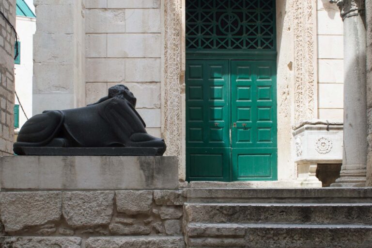 Front gate of the temple of Jupiter in the Diocletian's Palace in Split, Croatia, beautiful restored historic building with green door and guarded by Egyptian sphinx