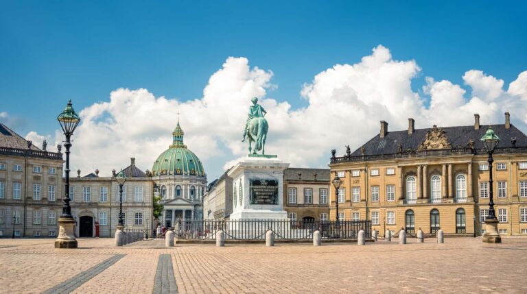 Bronze cast equestrian statue of King Frederik V among palaces in Amalienborg and facade of Frederik's Church in the background, in Copenhagen, Denmark