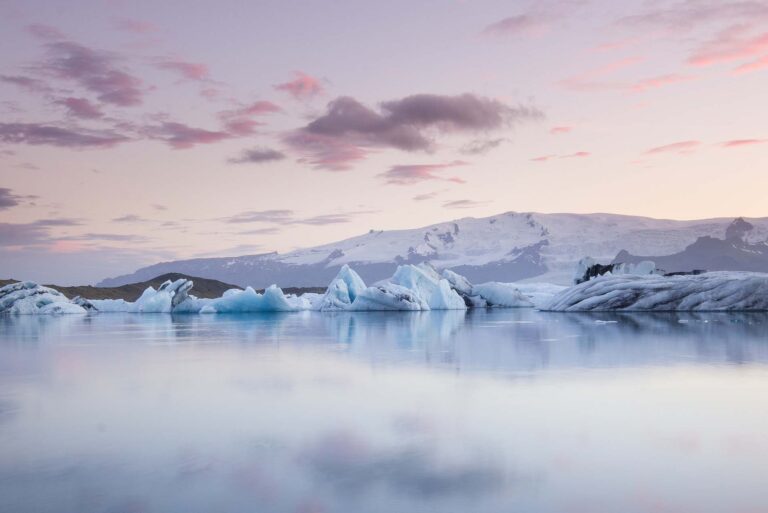Giant pieces of ice flowing on and reflecting in cold lake with