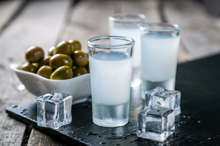 Traditional greek vodka - ouzo in shot glasses on rustic wood background