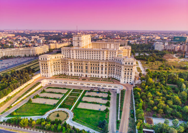 Parliament building or People's House in Bucharest city. Aerial view at sunset with abstract pink sky
