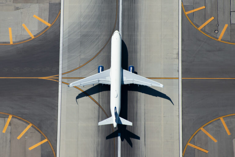 Aerial view of narrow body aircraft departing airport runway. To